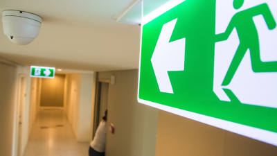 Somebody evacuating with a fire safety exit sign featured